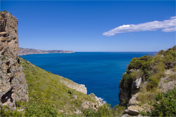 Hiking towards the watchtower of Cap d'Or gray rocks and greenery looking out towards a bright blue sea