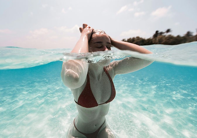 dress code for women in the Maldives a woman in crystal clear water, wearing a black bikini