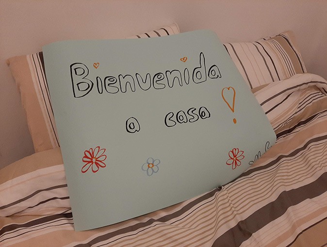 Leaving your home country to live abroad A hand written sign placed on a bed reading 'Bienvenida a casa'