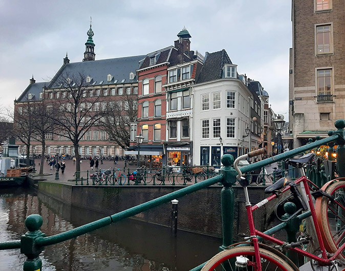 historic buildings to visit in Leiden part of a bicycle and bridge in the foreground with a canal and historic building in the background