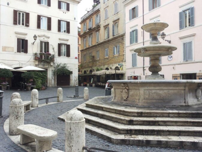 Rome in one day An empty square with an old, stone fountain and several old buildings in the background