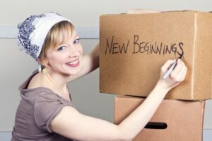 completing your moving abroad checklist woman writing on moving boxes
