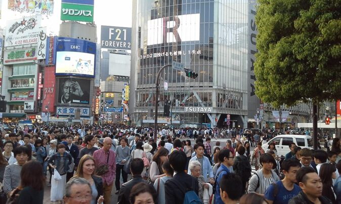 a very crowded pedestrian crossing with modern highrise buildings in the background