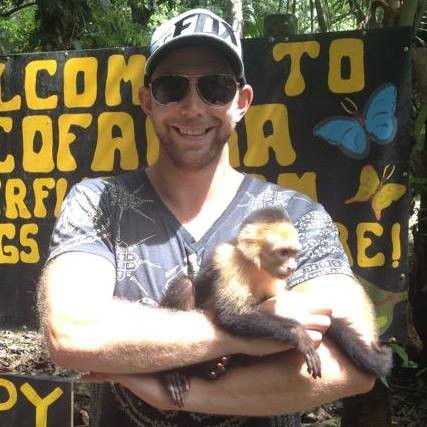living in Costa Rica a man with a baseball cap and sunglasses, holding a monkey