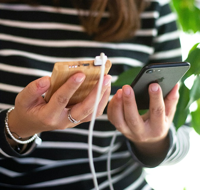 One of the best travel accessories Female hands holding a phone connected with a white wire to a power bank