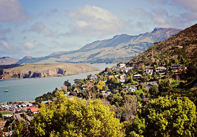 Houses in green hills alongside a large body of water