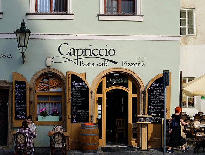 Enjoying life in Prague Green exterior of a restaurant with the name 'Capriccio' written on the wall and several people sitting on a terrace in front of it