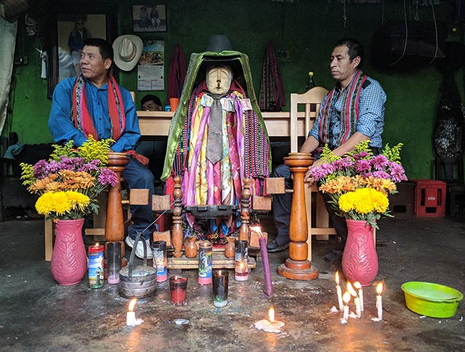 two men sitting with the Mayan folk saint Maximón