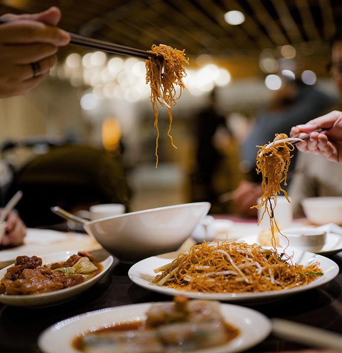 plates of Chinese food and two hands with chopsticks, in Shanghai, China