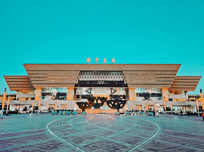 Zhengzhou, China A large, empty square in front of a large orange and brown building with Chinese writing on top of it