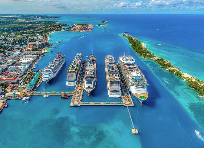 Reasons to go on a cruise 5 cruise ships docked surrounded by turquoise waters and parts of a tropical island