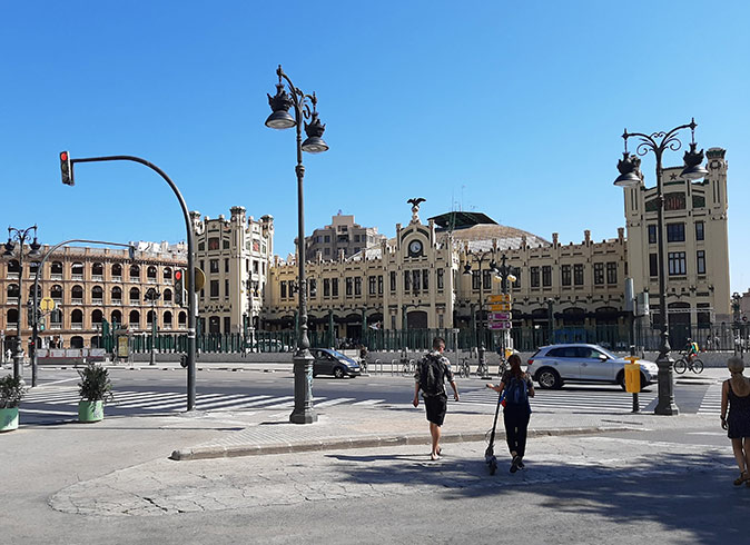 What to do in Valencia: visit the central train station pedestrians and several cars in front of a historic train station