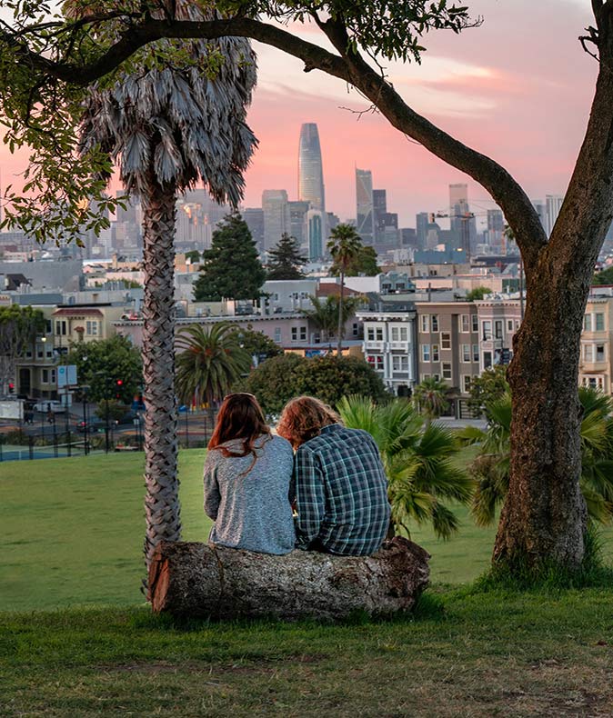 two expats sitting on a log in a park overlooking San Francisco