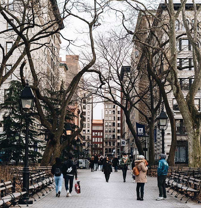 Life in New York people walking in Greenwich Village surrounded by buildings and bare trees