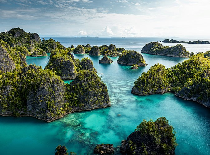 Small rocky island covered with greenery, surrounded by turquoise waters