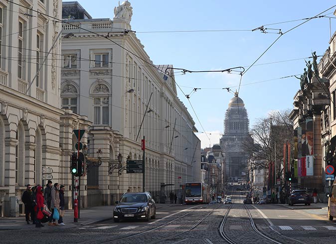 a wide street with several cars in the center of Brussels surrounded by historic buildings
