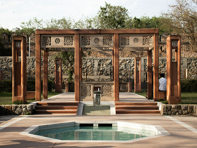 A fountain with a large pagoda behind it with a man in a white shirt