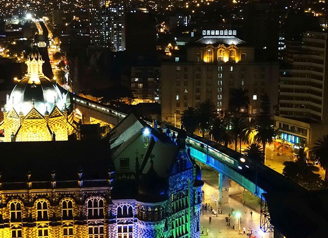 Safety for expats in Medellin Aerial view of Medellin at night showing dimly lit highrise buildings, some palm trees and some people on the street
