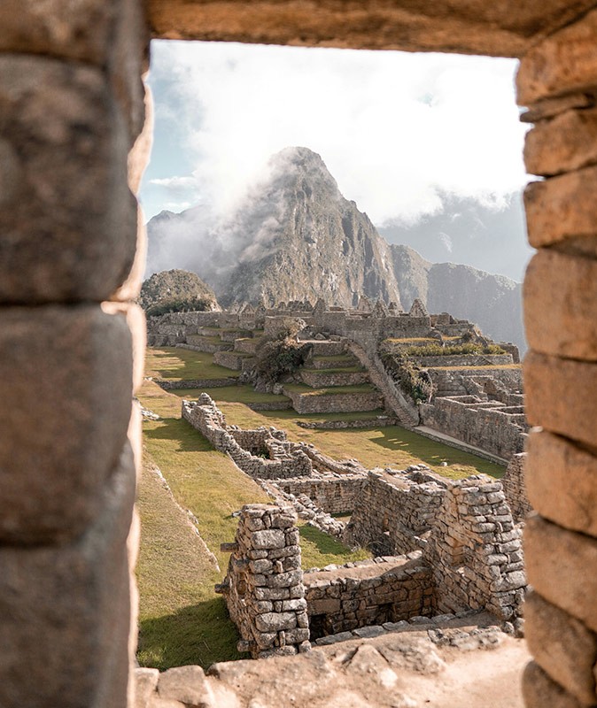 Entering Machu Picchu view through a stone window of the famous Machu Picchu ruins on a misty day