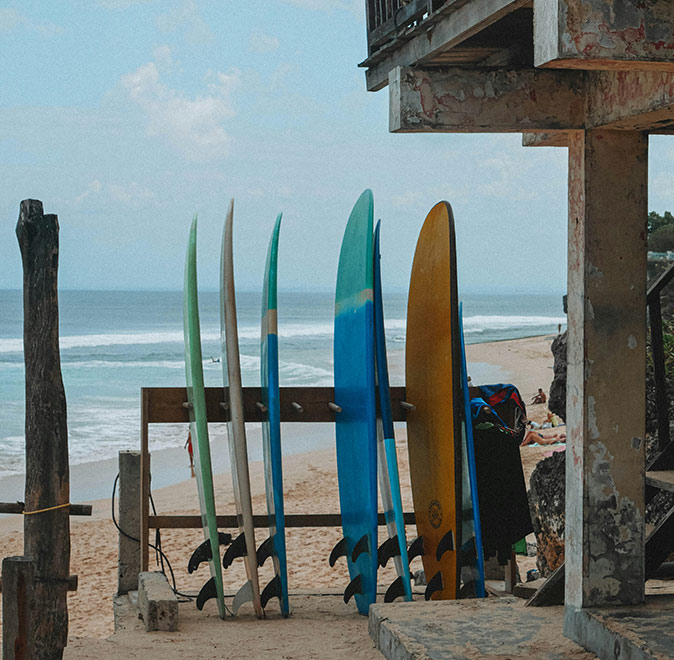 Digital nomad life in Uluwatu, Bali Surfboards lined up against a wooden structure on a sandy beach