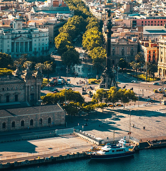 Expat life in Barcelona, Spain Aerial view of a built up city with a dock with one boat in the foreground