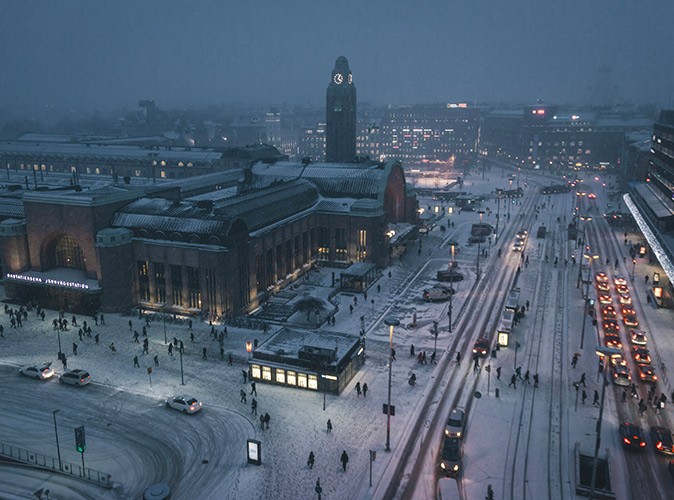 Life in Helsinki in winter A gray and snowy aerial view of a city with several buildings, people walking and cars driving
