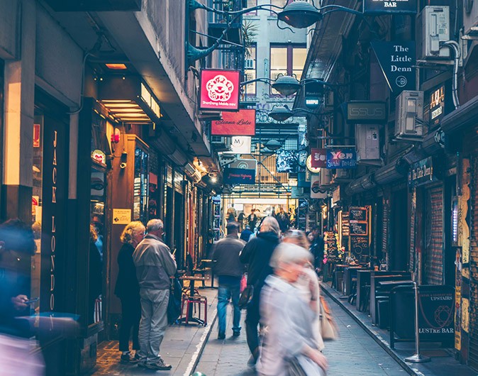 Safety in Melbourne A dark alley with several people walking, some shop signs and some graffiti