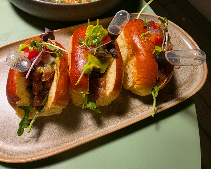 Rooftop restaurant in Valencia 3 small buns with raw tuna and greens on a white plate