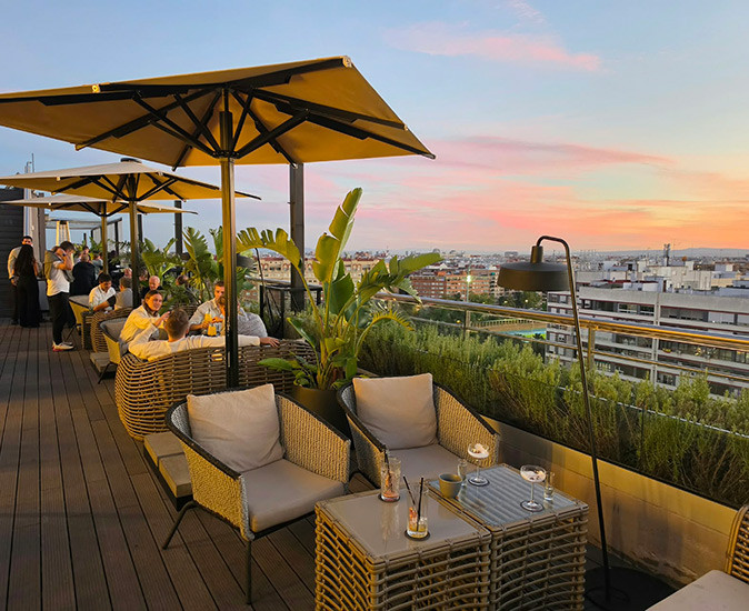 Valencia's skybar at Novotel A warm sunset over a rooftop bar in Valencia showing several tables with people enjoying drinks
