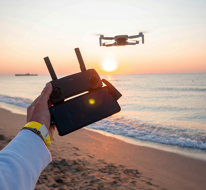 One of the best gifts for digital nomads A drone in the air with a hand holding the drone controller