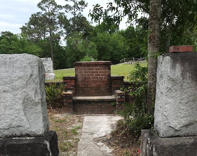 One of the quirky things to do in Cassadaga A brick chair at a cemetery surrounded by trees