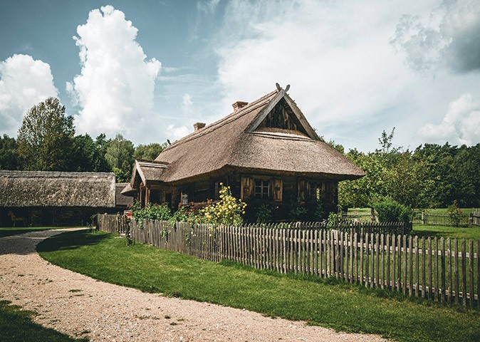 Lithuania's historic and cultural sites to visit An old wooden building with a sandy footpath and a wooden fence