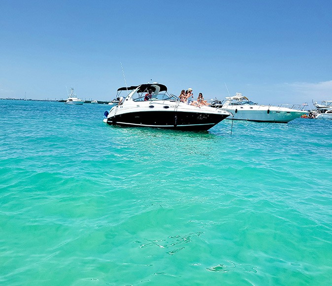 Tips for boating in Miami Several motorboats anchored in crystal clear turquiose water