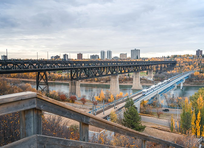 Tips for living in Edmonton A train track with a train approaching and a city skyline in the background