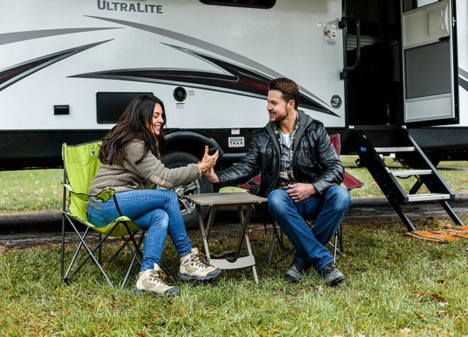 Things to know before RVing in Maine A man and a woman sitting on chairs in front of their large RV