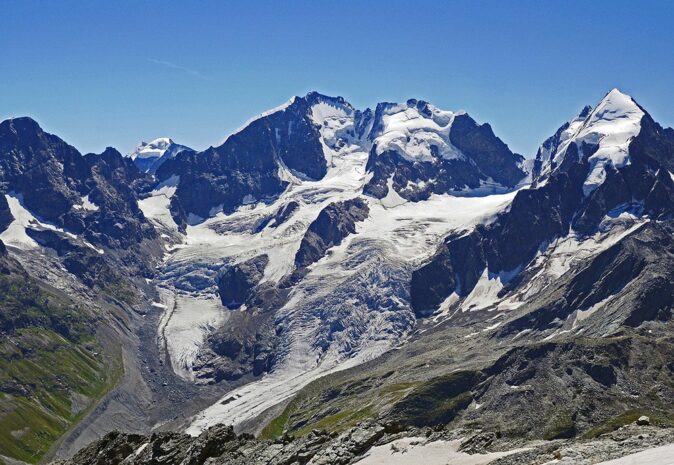 Best views in Switzerland: Val Roseg A green and gray valley with a mountain range covered with snow in the background