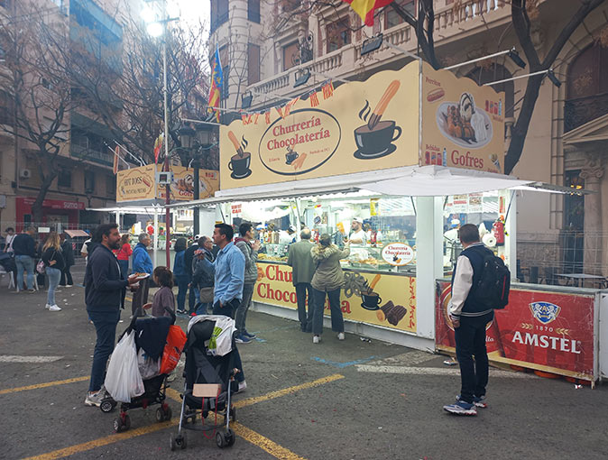 Food stand selling buñuelos and churros during Las Fallas in Valencia several people in front of 2 food stands