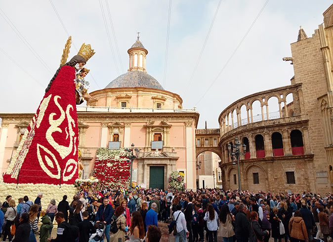 Ofrenda de Flores, part of Las Fallas in Valencia in March A large statue decorated with flowers, a big crowd and a cathedral in the background also decorated with flowers