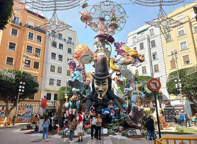 everything you need to know about celebrating Las Fallas in Valencia people surrounding a large sculpture made up of several figures, with apartment buildings in the background