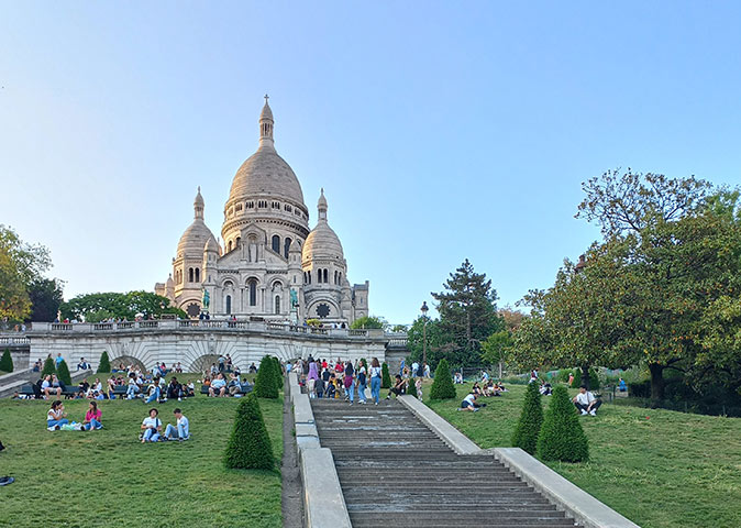 The famous Sacre Coeur in Paris with people sitting on the grass in front of it