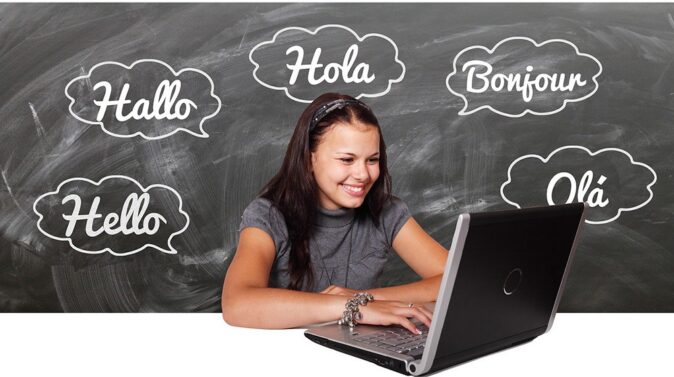 working and living abroad A girl smiling while looking at her laptop, with the word 'Hello' written in several languages in the background