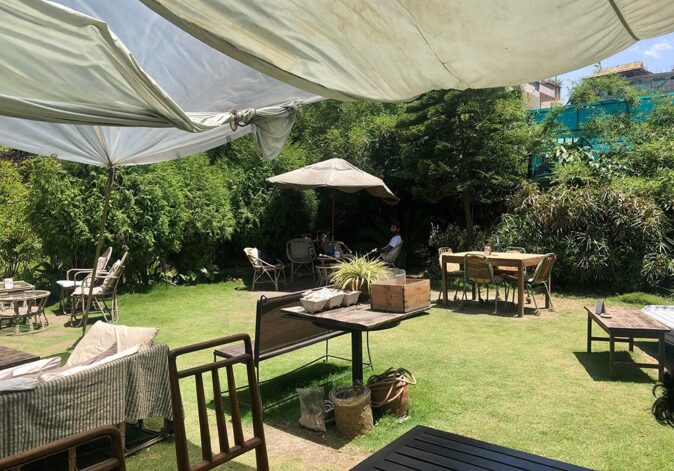 Best coffee shop in Kathmandu: Salon de Kathmandu A courtyard with several sets of tables and chairs, surrounded by green bushes