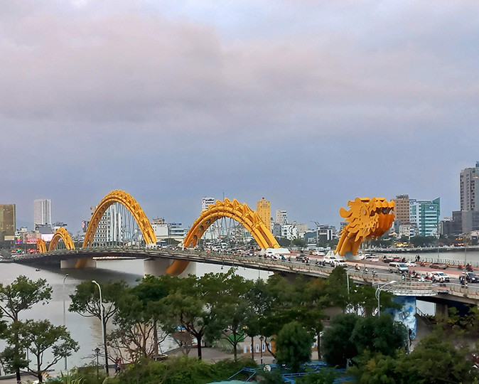 A 2 day Da Nang itinerary A long bridge with a bright yellow dragon as arches and cars driving across the bridge