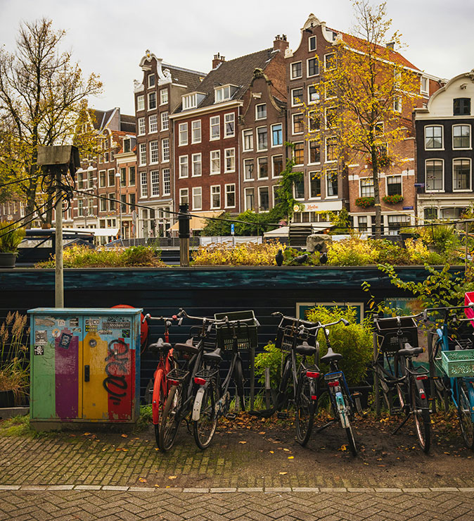 Amsterdam travel tips Several parked bicycles in front of typical Amsterdam houses made of brown bricks and white windows