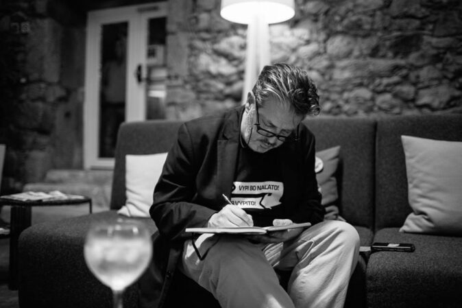 expat living in Vilnius black and white picture of a man sitting on a couch writing something in a notebook