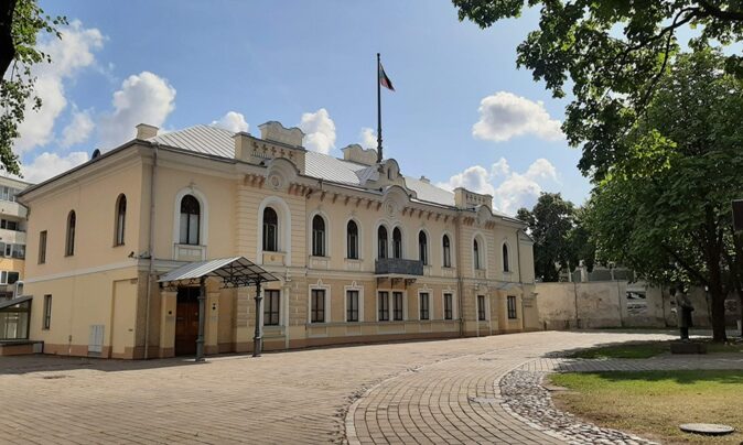 The Historical Presidential Palace - What to see in Kaunas a Neo-baroque building with the Lithuanian flag in the middle and trees around it