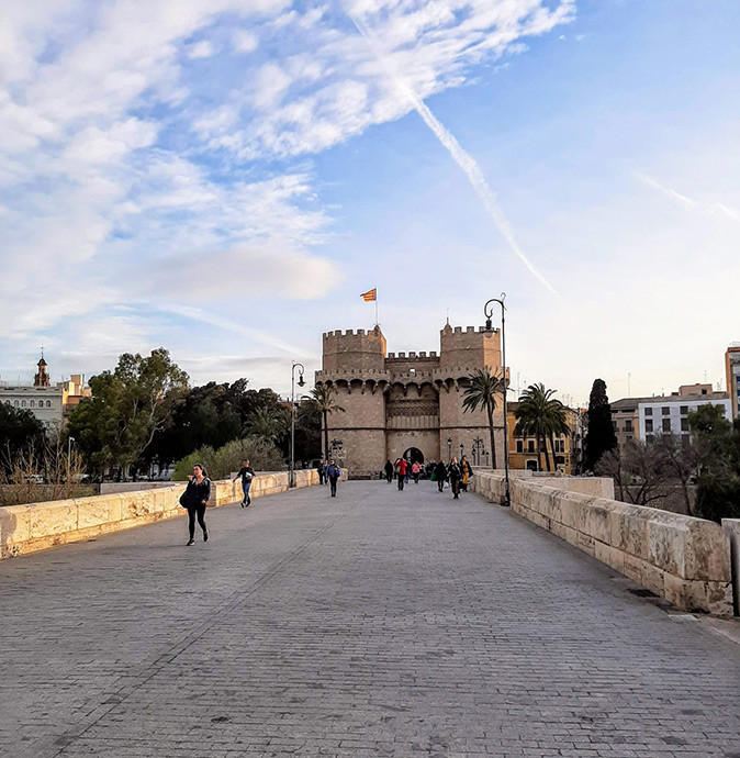 The cost of living in Valencia as a retiree A stone bridge leading to a historic city gate in Valencia