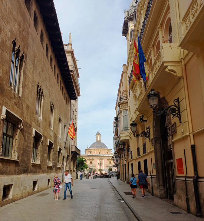 Is Valencia, Spain a good place to retire? A narrow city street with pedestrians and a historic church in the background