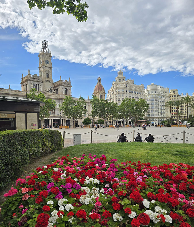 Retiring in Valencia, Spain A typical Spanish city square with flowers in the foreground, various people and historic buildings in the background