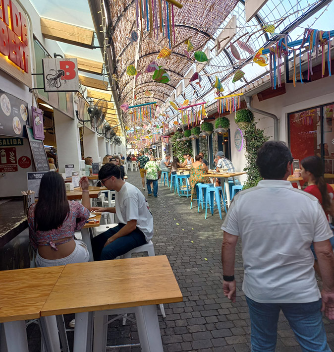What Denia is really like A food court with several eateries, people walking and people sitting at tables